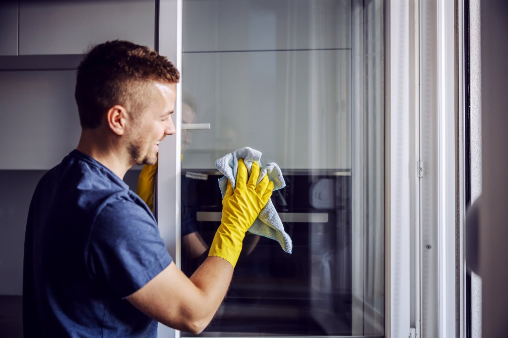 mann reinigt kunststofffenster